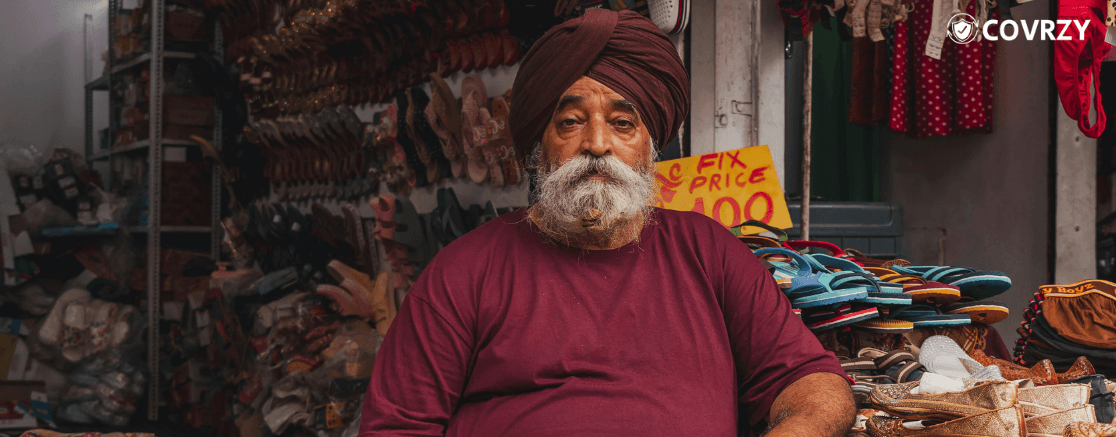 an Indian shopkeeper in his middle age sitting infront of his shoe shop