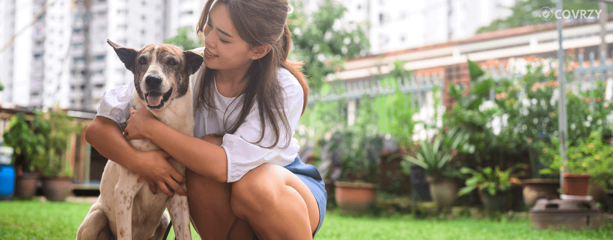A young woman in casuals embracing her pet dog