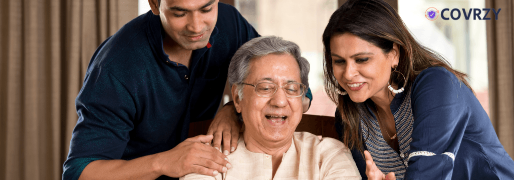 An elderly Indian man with a man and a woman looking at a piece of paper, they all seem happy and smiling