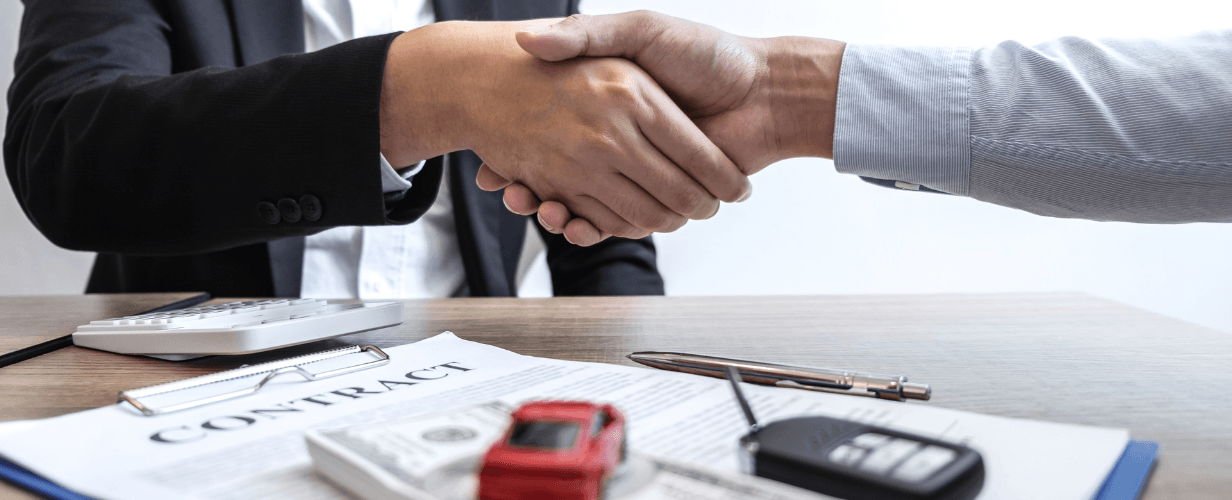 two people shaking hands of each other, a paper and a white calculator lying below
