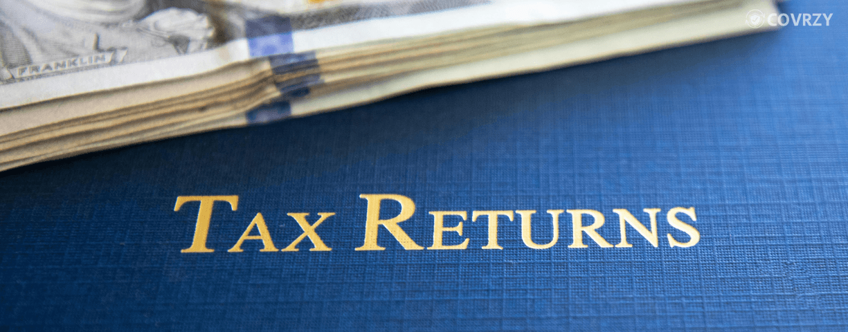 Few currency notes lying on a blue texture with Tax Returns written on it